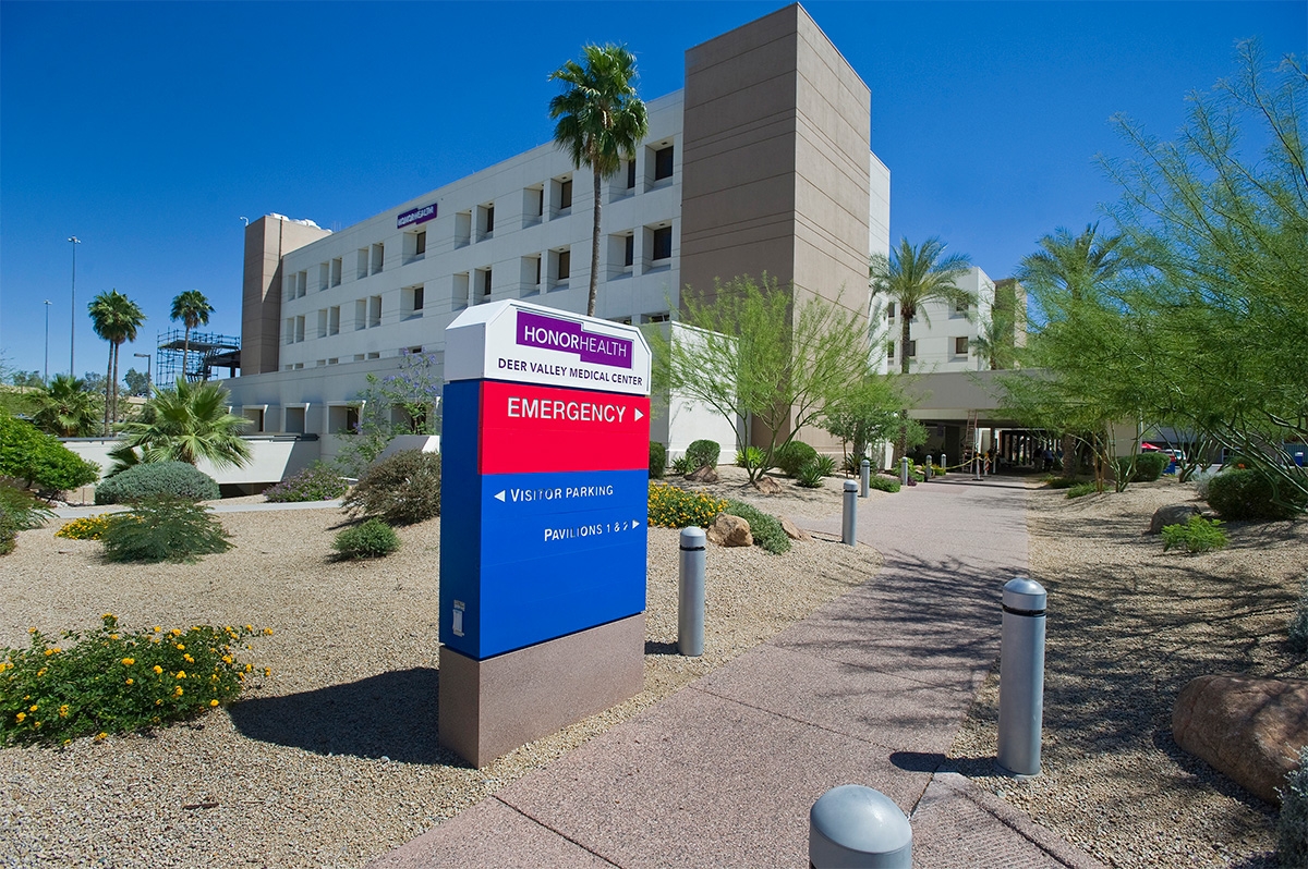 A directional sign for HonorHealth Deer Valley Medical Center stands near the facility’s entrance, with emergency and visitor parking information visible, surrounded by desert landscaping.