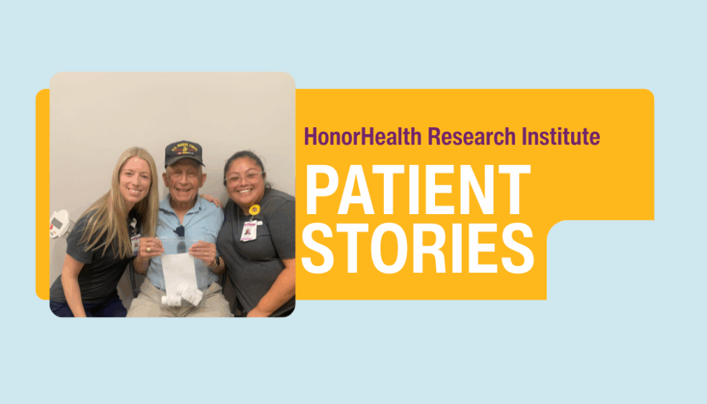 An elderly man sits between two smiling healthcare workers in front of a wall that reads 